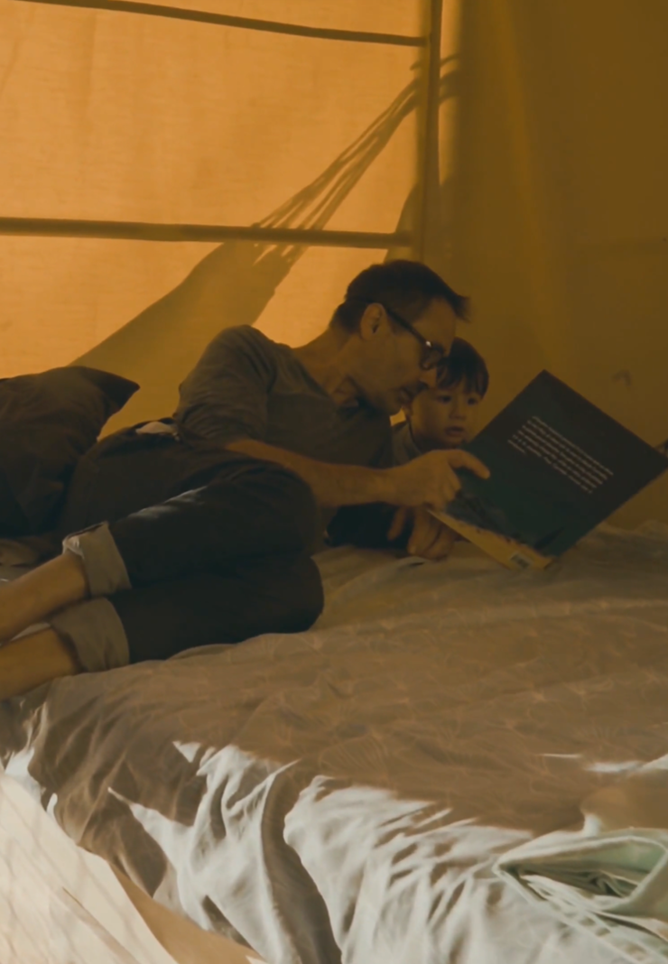 A guest reading with a child on the double bed on board